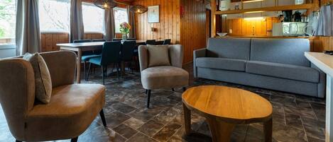 Interior acogedor de una cabaña con comedor, sofá y mesa de madera.