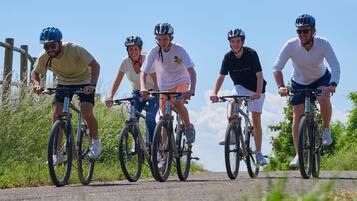 A group of cyclists on a paved path with a wooden fence on one side and greenery on the other.