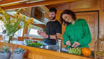 Une cuisine avec des meubles de rangement en bois, un évier et un plan de travail sur lequel se trouvent un vase de fleurs, un saladier et un panier de fruits.