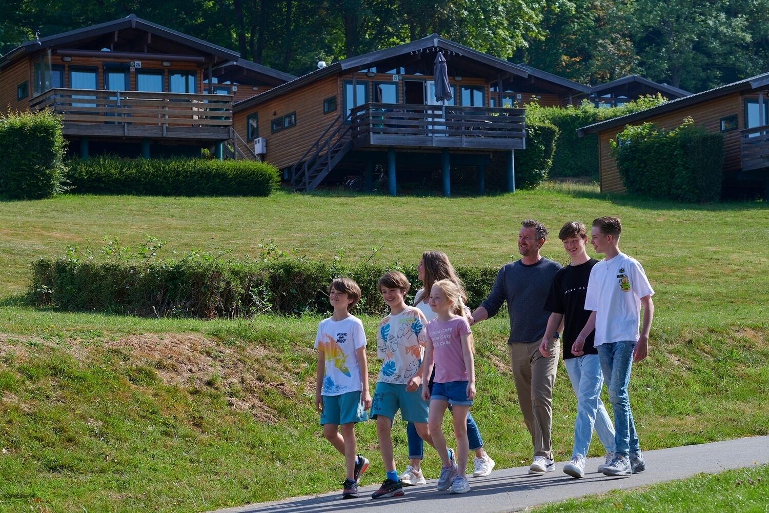 A family walking on a path with wooden cabins in the background.