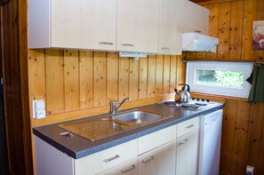 Compact kitchen with dishwasher, granite countertop, and stainless steel sink, offering a view of the outdoors.