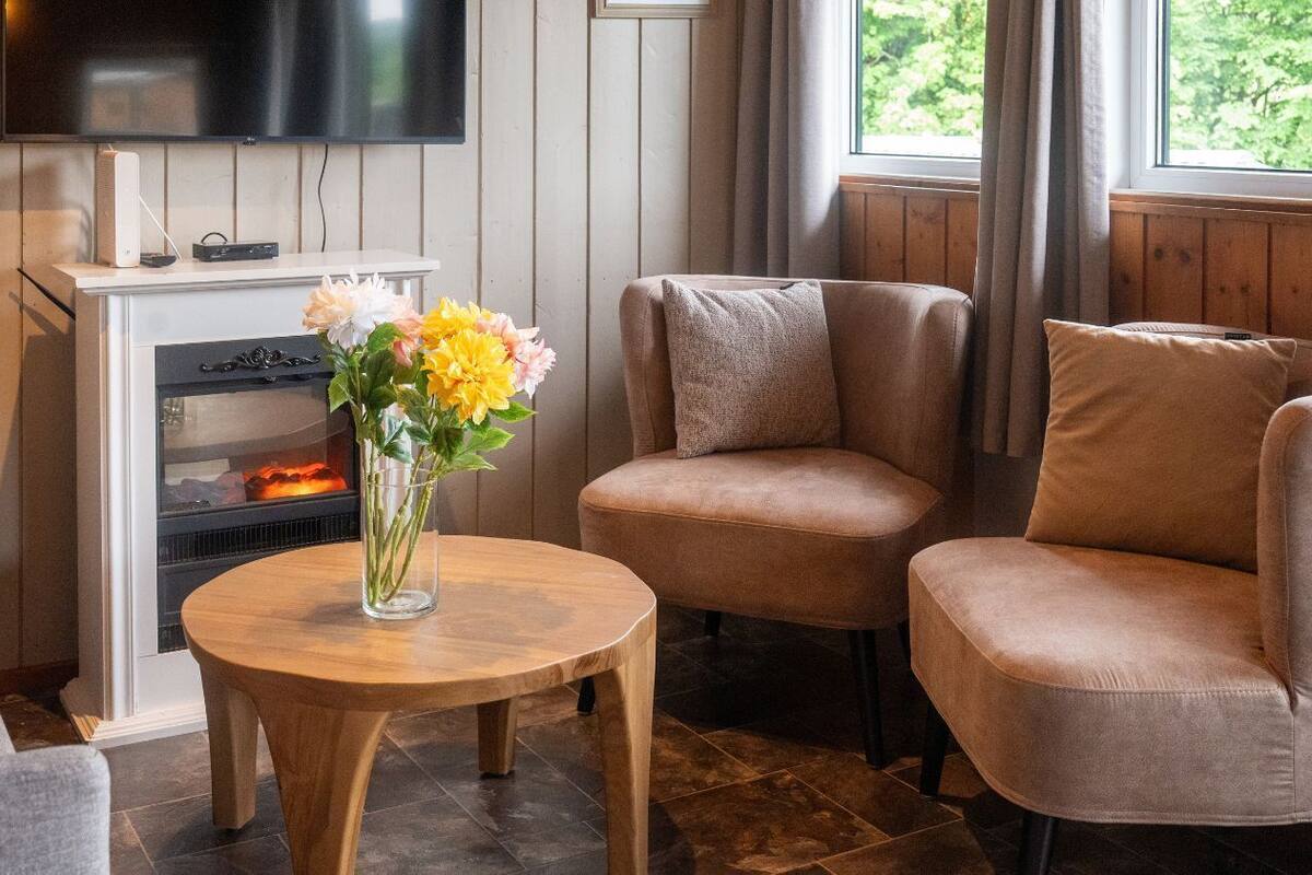 Un salon chaleureux avec une cheminée, un téléviseur et un coin salon confortable.