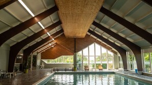 Una piscina interior con techo alto y ventanas amplias.