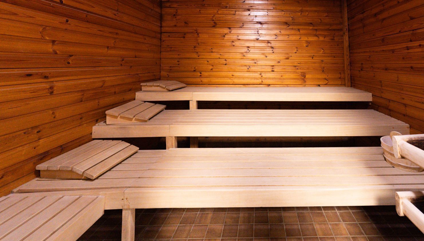 Una sauna con panche in legno e pavimento piastrellato.