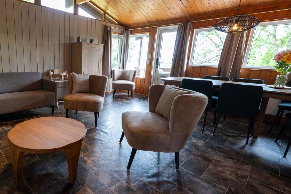 Un intérieur chaleureux avec un canapé, des fauteuils, une table à manger et un plafond en bois.