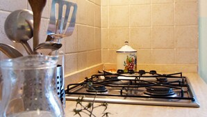 Une cuisine équipée d’une cuisinière à gaz, avec une casserole sur le feu et divers ustensiles, comme une fourchette et une spatule.