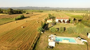 Une propriété rurale dotée de champs, d’une piscine et d’une maison au toit rouge.