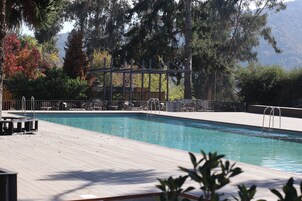 Una piscina al aire libre de temporada, sombrillas, tumbonas