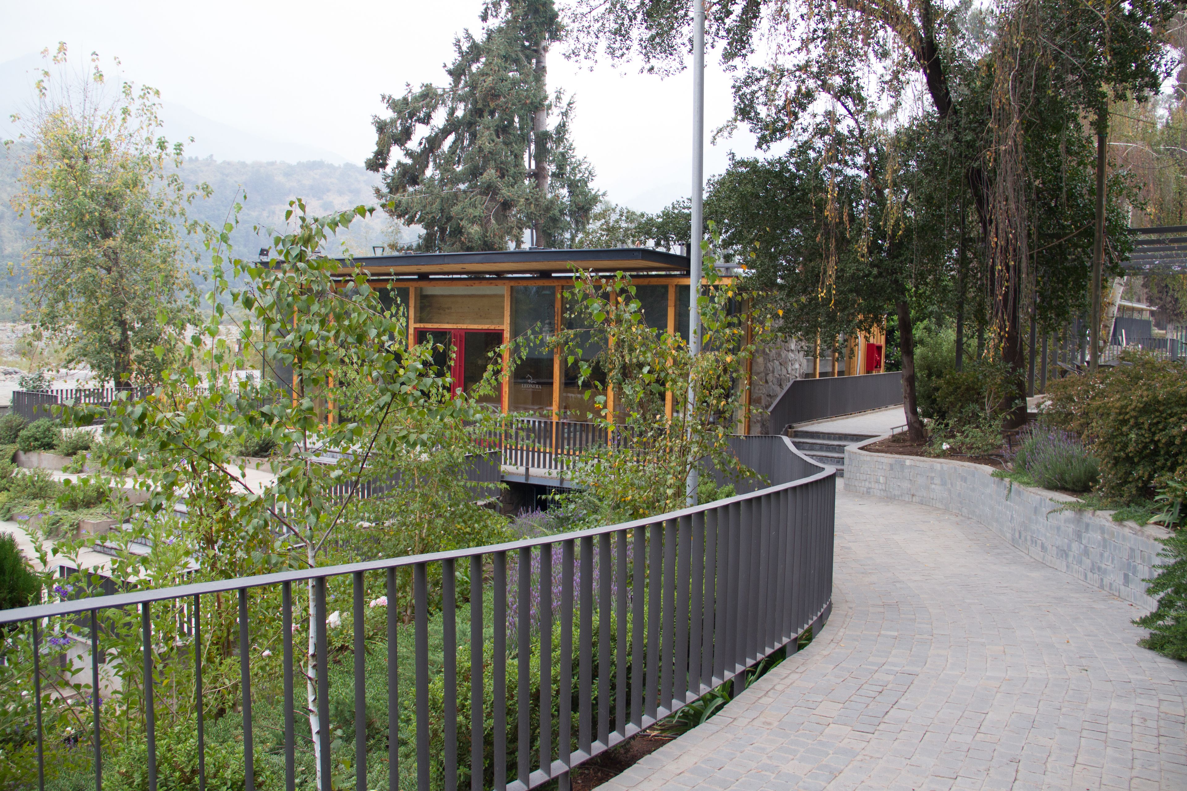 A modern building with a glass facade, surrounded by lush greenery and a paved walkway.
