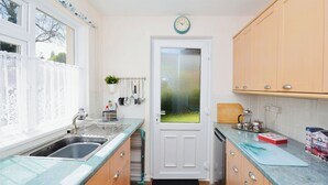 A compact kitchen with a double sink, a coffee machine, and a small window.