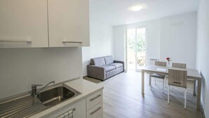 A modern kitchen with white cabinets, a stainless steel sink, and a dining area with a table and chairs. - Apartment "E" Balcony - Levanto Cinque Terre (Levanto)
