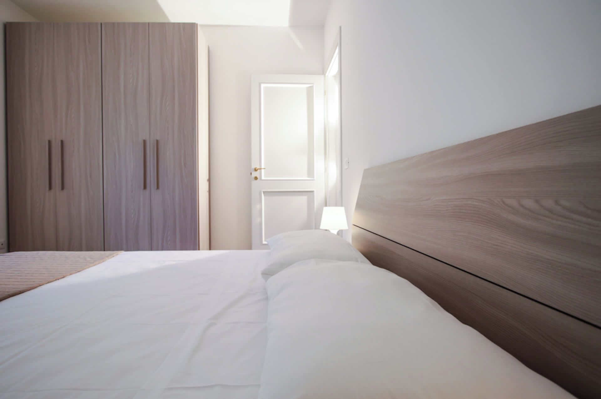 Ein Schlafzimmer mit einem Bett, einem Kleiderschrank und einer Tür zu einem anderen Raum.