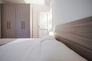 A bedroom with a bed, a wardrobe, and a door leading to another room.
