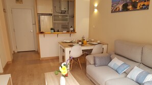 Eine moderne Wohnung mit Essbereich, Küchenzeile und Wohnzimmer mit Sofa und Couchtisch.