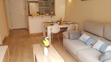 Eine moderne Wohnung mit Essbereich, Küchenzeile und Wohnzimmer mit Sofa und Couchtisch.