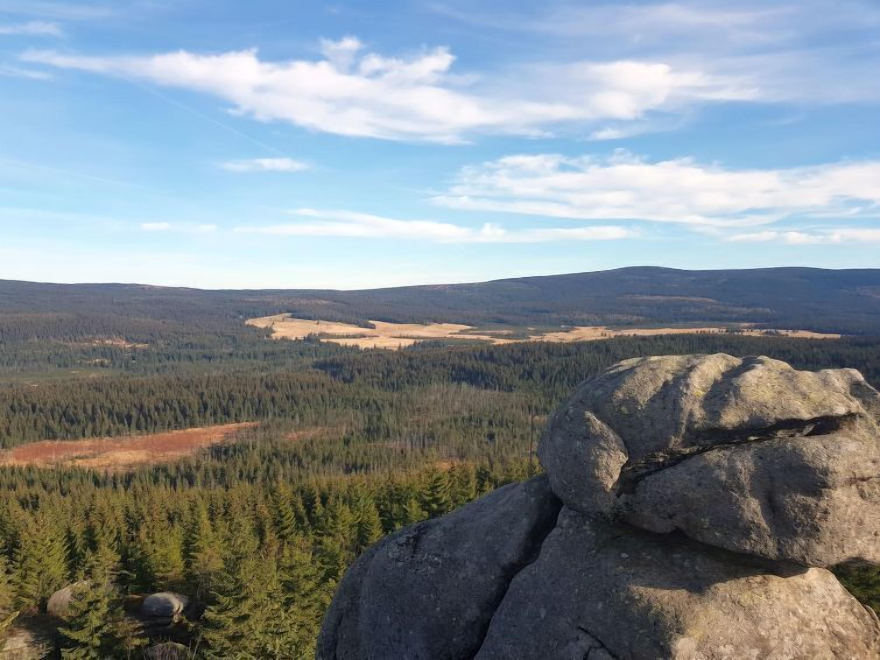 Un paisaje montañoso con bosques densos y una formación rocosa destacada en primer plano.