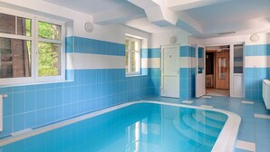 A swimming pool with blue and white tiled walls, a door, and a window.
