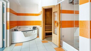 A modern bathroom with a curved bathtub, a wooden sauna, and a glass shower enclosure.