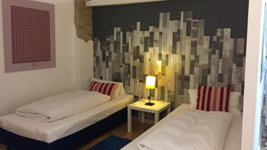 A room with two single beds, a small table with a lamp, a decorative wall, and a partial view of a window. - Loft 1. 3 in the heart of Berlin (Bezirk Friedrichshain-Kreuzberg)