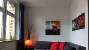 A modern living room with a grey sofa, red cushions, a glass coffee table, and a vase with branches. - Loft 1. 3 in the heart of Berlin (Bezirk Friedrichshain-Kreuzberg)