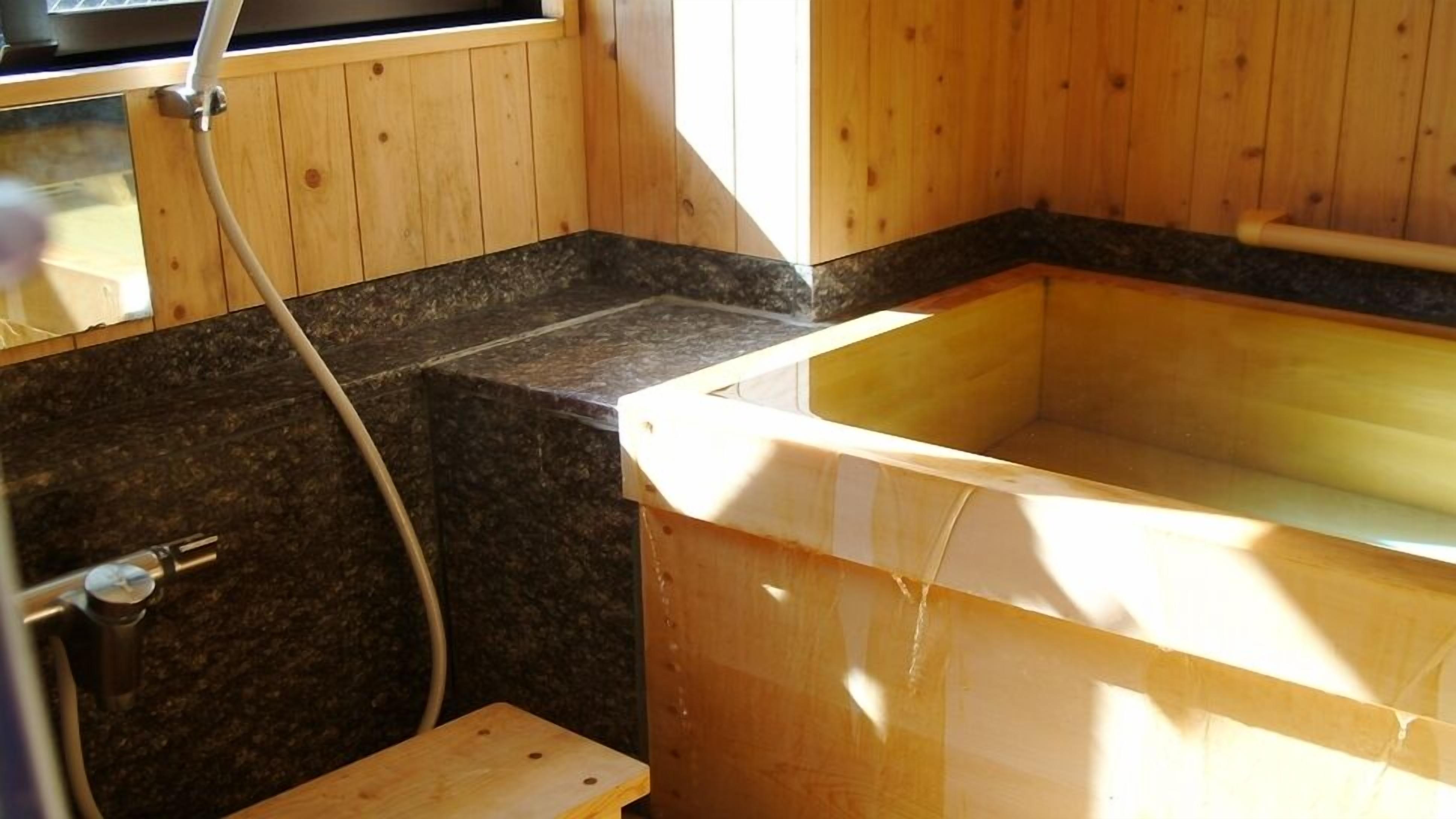 Een houten interieur met een bad, douche en een granieten aanrecht.