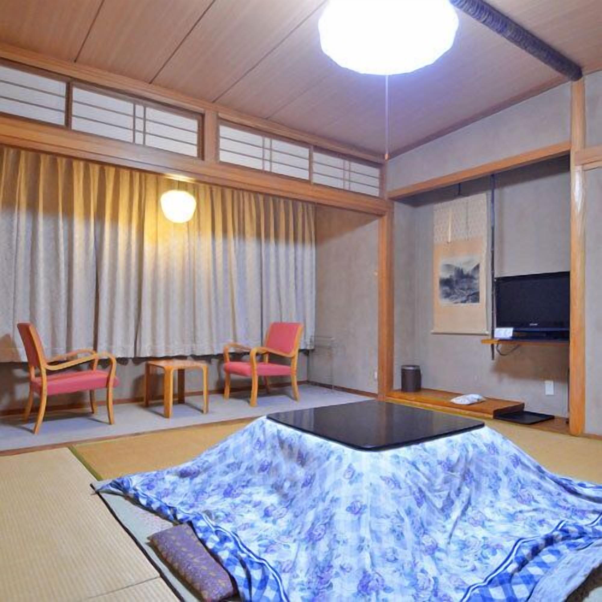 Een traditionele Japanse kamer met tatami vloeren, een futonbed, houten meubels en een televisie.