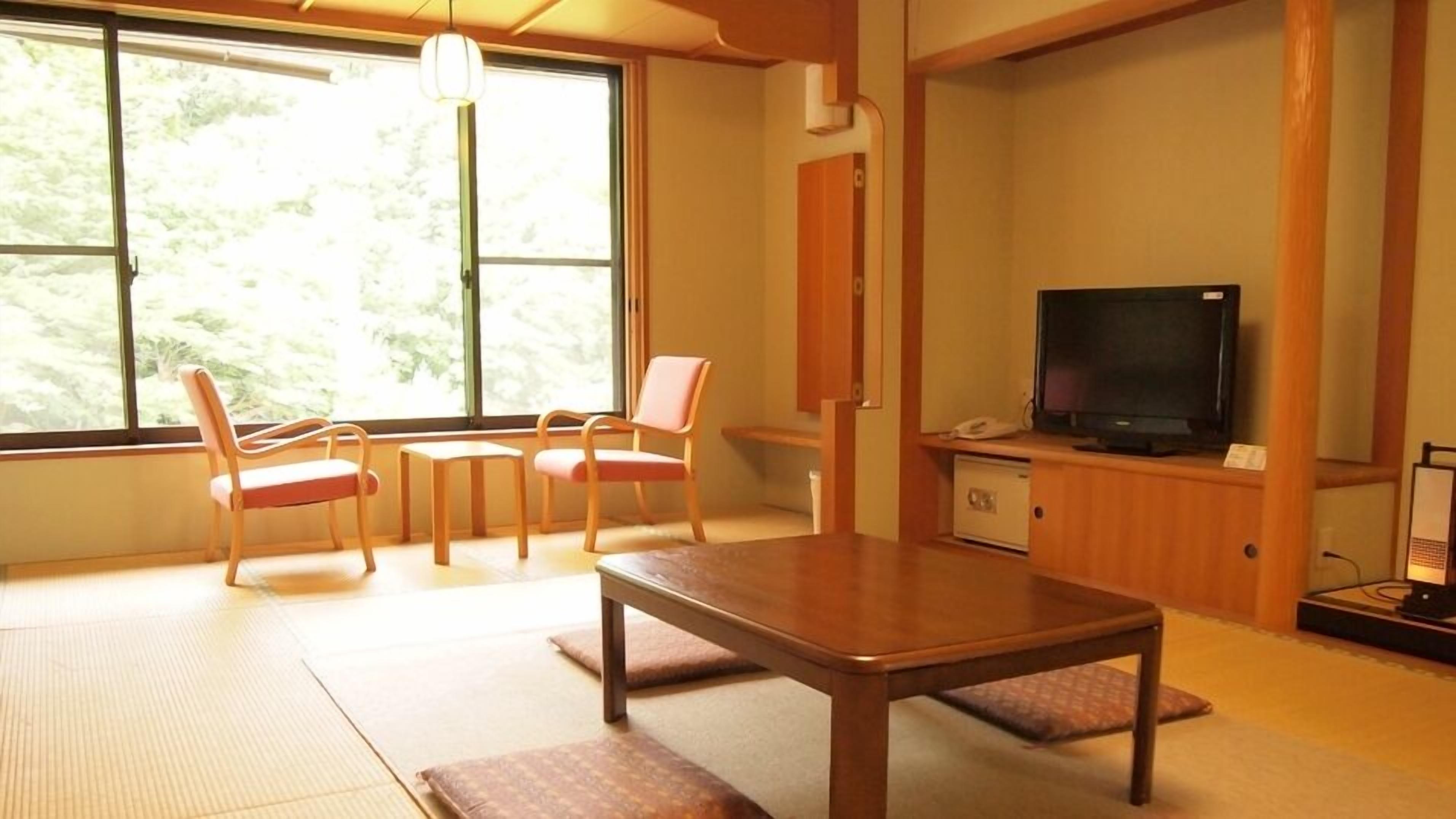 Een kamer met tatami matten, een houten tafel en een televisie.