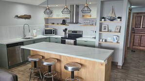 Een moderne keuken met een centraal eiland, barstoelen en hanglampen.