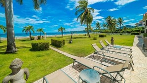 Een resort met een zwembad, ligbedden en palmbomen.