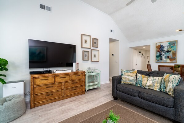 A modern living room with a flat-screen TV, wooden dresser, and a gray sofa. - Charming 2BR/2BA Villa With Golf Course View! NO pets (Johns Island)