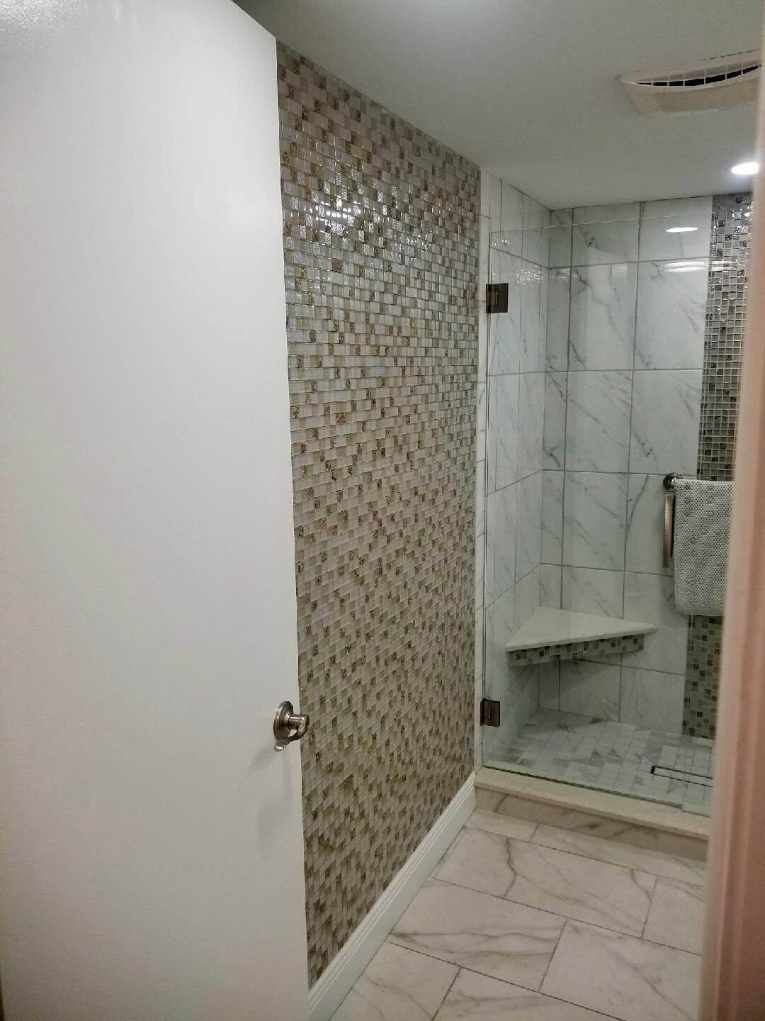 Un baño con zona de ducha, paredes con azulejos y suelo de mármol.