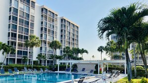 A hotel with a swimming pool, lounge chairs, and palm trees. - SHELLebrations: Gulf-Front Penthouse Paradise on Fort Myers Beach, Florida (Fort Myers Beach)