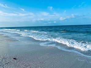 Une plage avec un ciel dégagé et une mer calme.