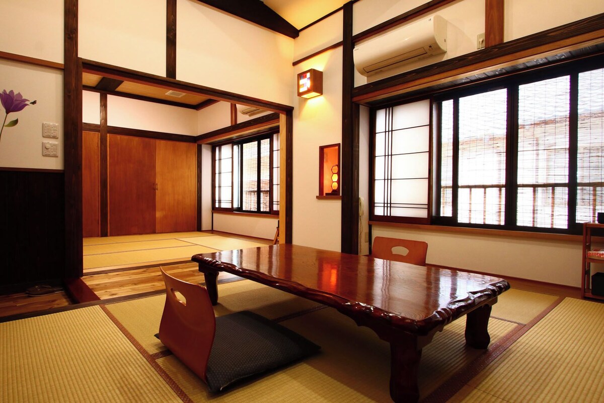 Una habitación japonesa tradicional con suelo de tatami, una mesa de madera y puertas correderas.