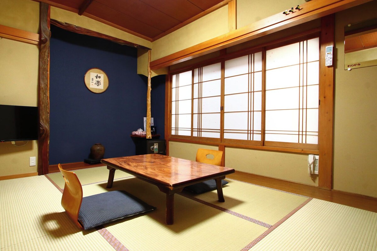 Ein traditioneller japanischer Raum mit Tatami-Böden, einem niedrigen Tisch und einer Schiebetür.