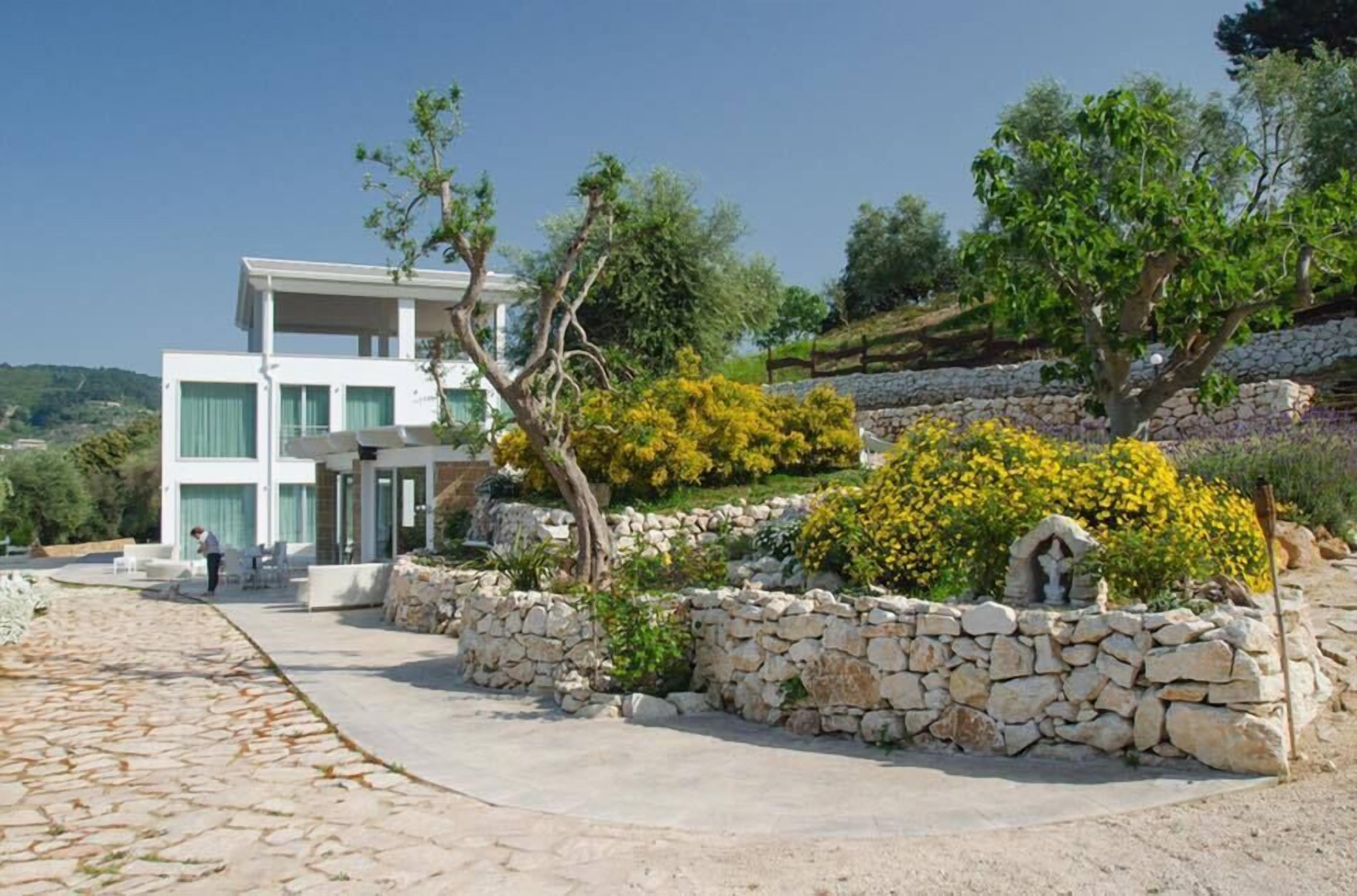 Un edificio moderno a due piani con un vialetto in pietra che conduce a una zona relax.