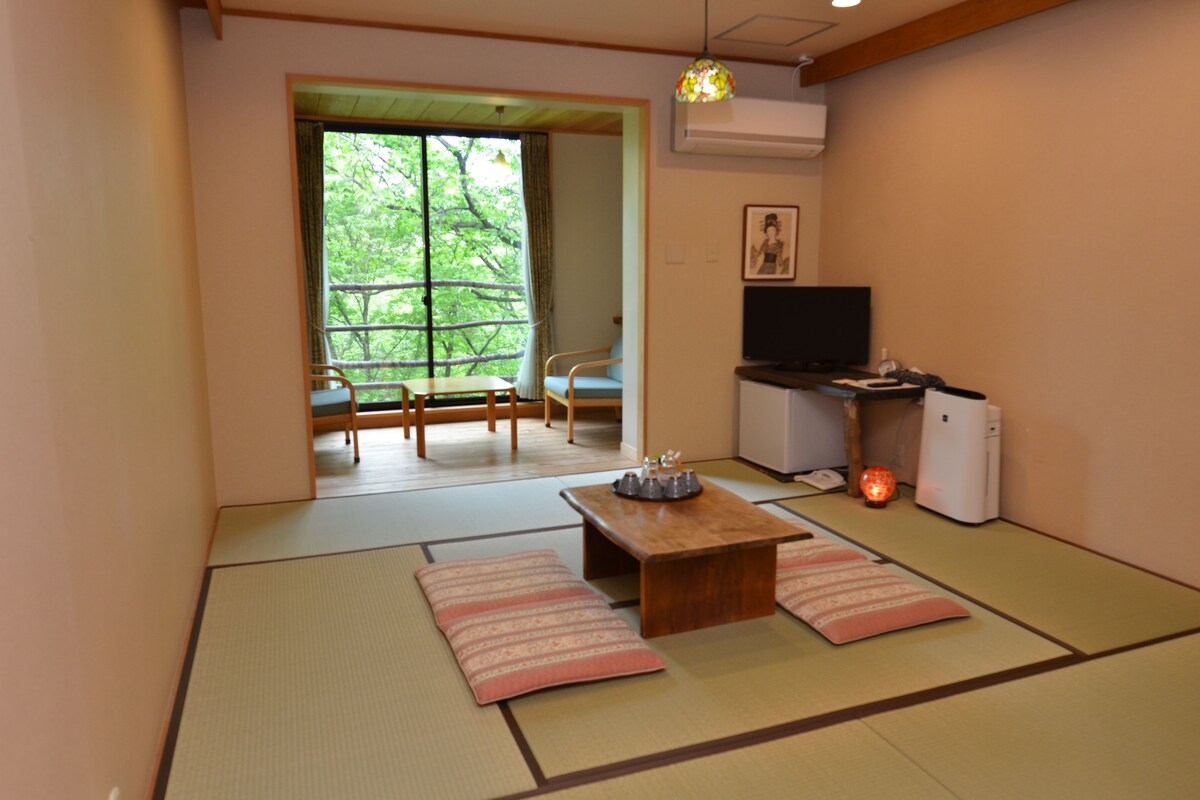 Habitació tradicional japonesa amb fons de tatami, una taula baixa i coixins, televisió i calefacció.