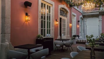 An outdoor seating area with tables and chairs, a wooden deck, and decorative lighting.