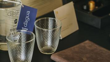 A bottle of d'Agua, two glasses, a card, and a wallet on a table.