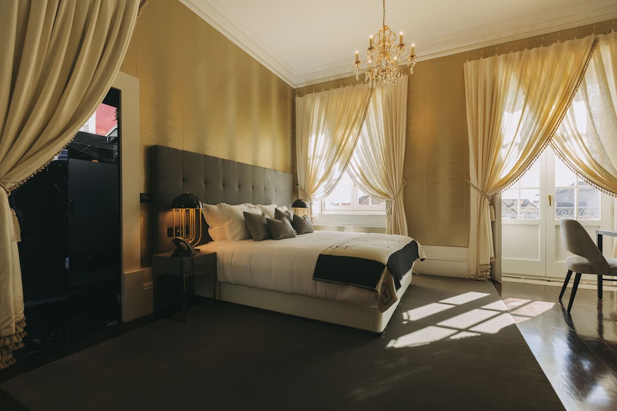 Une chambre à coucher avec un grand lit, une table de chevet, une chaise et un lustre.