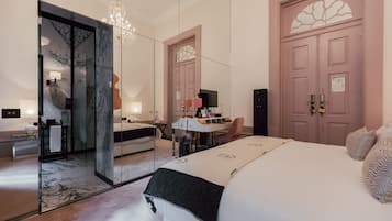 A modern bedroom with a large bed, a desk, and a mirror.
