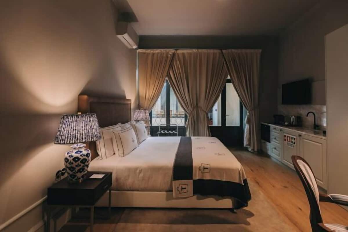 Une chambre d’hôtel avec un lit, une table de chevet, une lampe et une vue par la fenêtre.