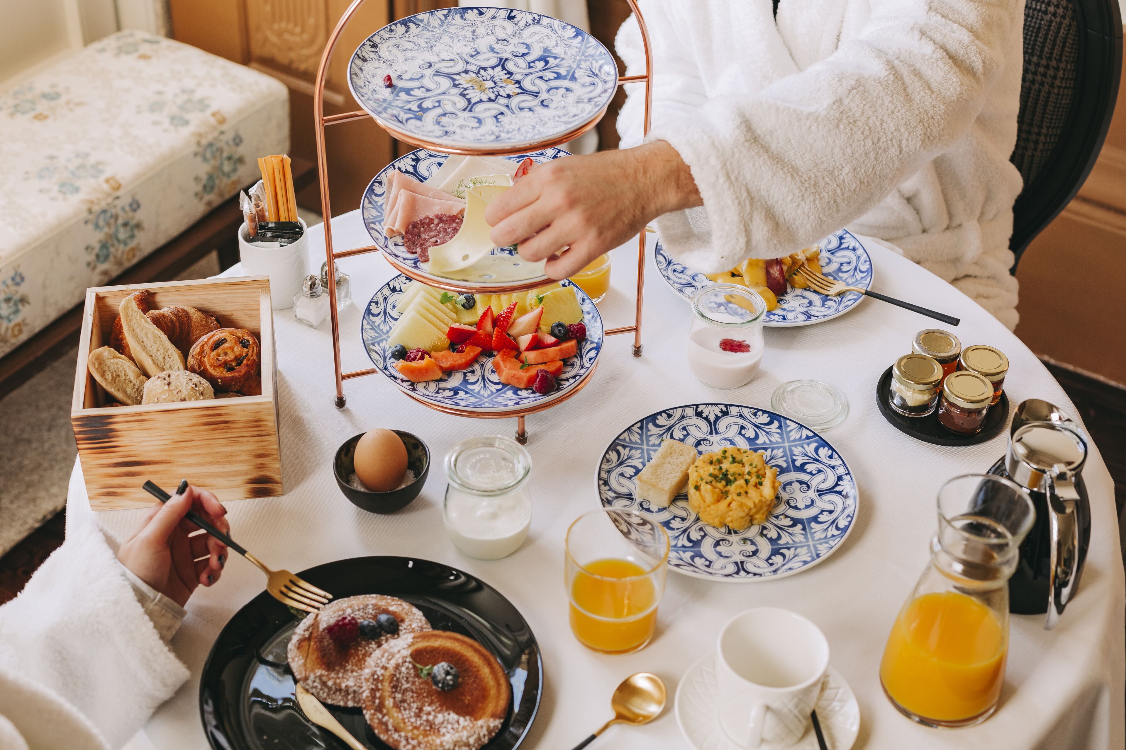 A breakfast setting with a three-tiered stand, plates of food, and various condiments.