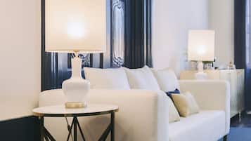 Una habitación de hotel moderna con un sofá blanco, una mesita redonda y una lámpara a juego.