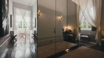 A spacious room with a large mirror, a wooden floor, and a view of a green landscape through a window.