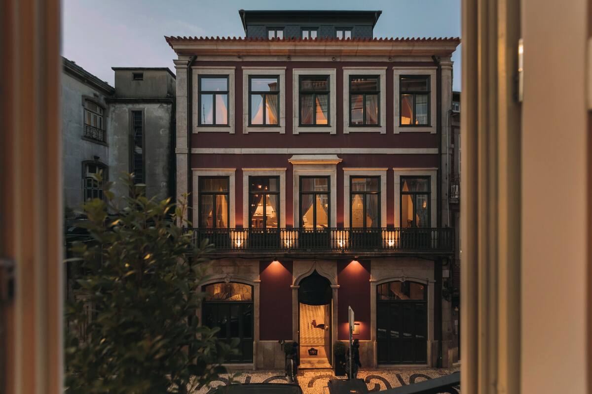 Un immeuble à plusieurs étages doté d’un balcon, de fenêtres en arc de cercle et d’une porte avec une petite marche menant à l’entrée.