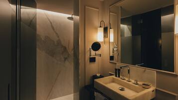 A modern bathroom with a large mirror, a sink, and a shower.
