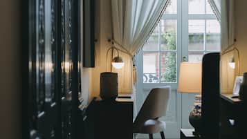 Ein Zimmer mit einem großen Fenster, einem Sessel, einer Lampe und einer Vase auf einem Tisch.