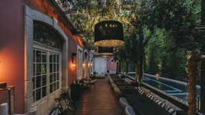 An outdoor seating area with tables and chairs, a bicycle, and a view of a river. - Torel Palace Porto (Porto)