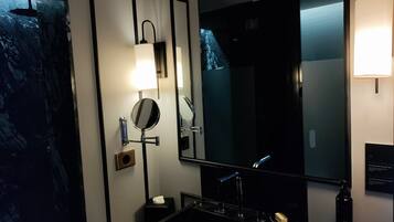 A modern bathroom with a black sink, a large mirror, and a wall-mounted light fixture.